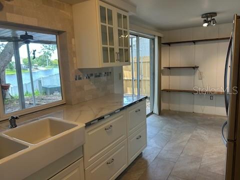 A kitchen features a farmhouse sink, white cabinetry, open shelving, and a view of water — 3601 LANDALE DRIVE, HOLIDAY, FL