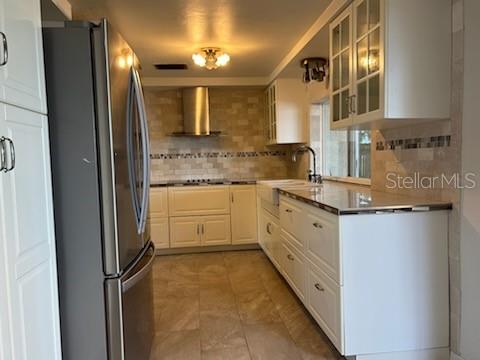 A kitchen featuring white cabinets, stainless steel appliances, a tile backsplash, and light-colored tile flooring — 3601 LANDALE DRIVE, HOLIDAY, FL