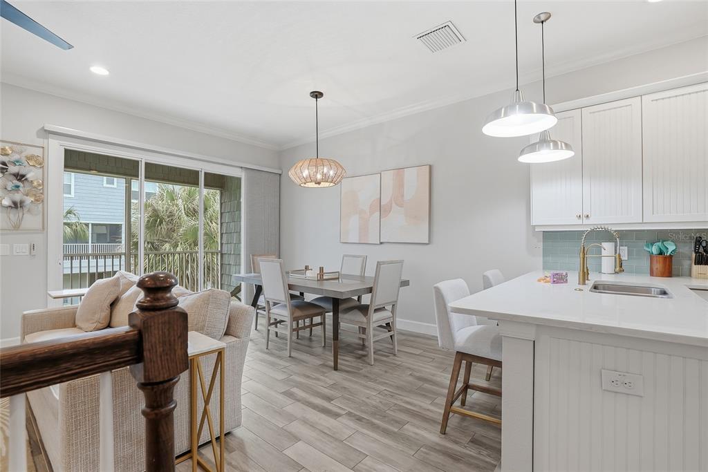 An open-concept kitchen and dining area features white cabinetry, a kitchen island, and sliding doors — 3162 MOORINGS DRIVE, ST PETERSBURG, FL