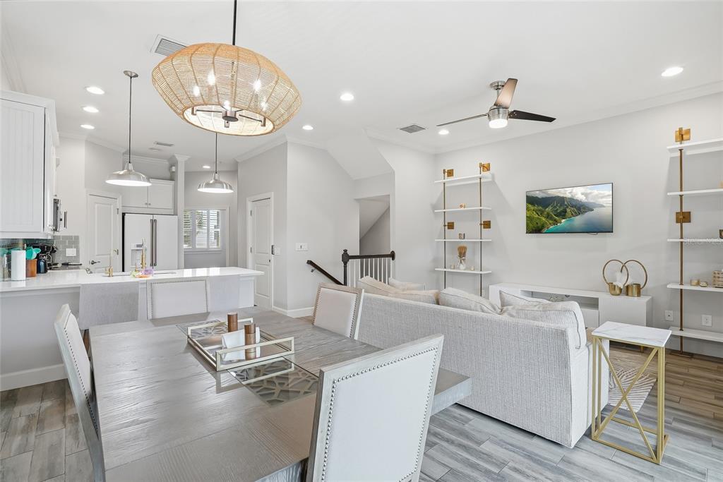 An open-concept living and dining area features a kitchen island, light wood floors, and shelving — 3162 MOORINGS DRIVE, ST PETERSBURG, FL
