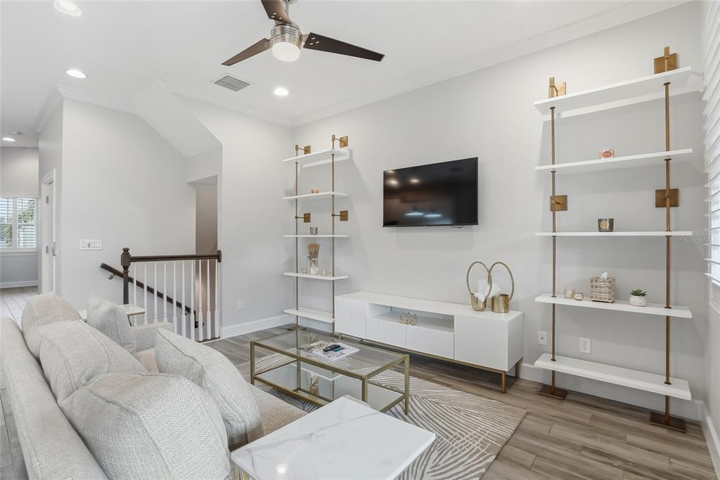 A living room features a white media console, two tall shelving units, and a sofa — 3162 MOORINGS DRIVE, ST PETERSBURG, FL