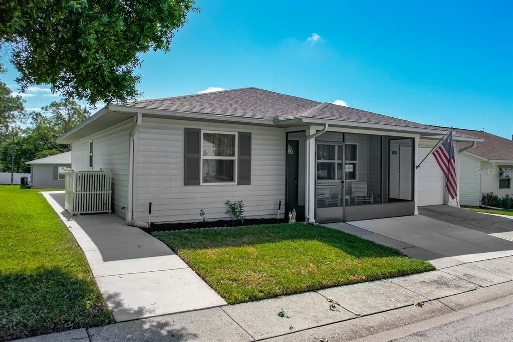 A single-story house with light gray siding, a screened-in front porch, and a concrete driveway — 3123 PRAIRIE DUNES CIRCLE W, LAKELAND, FL