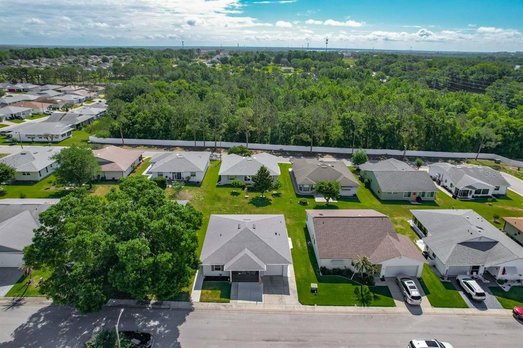 An aerial view shows a suburban neighborhood with single-family homes, green lawns, and surrounding trees — 3123 PRAIRIE DUNES CIRCLE W, LAKELAND, FL