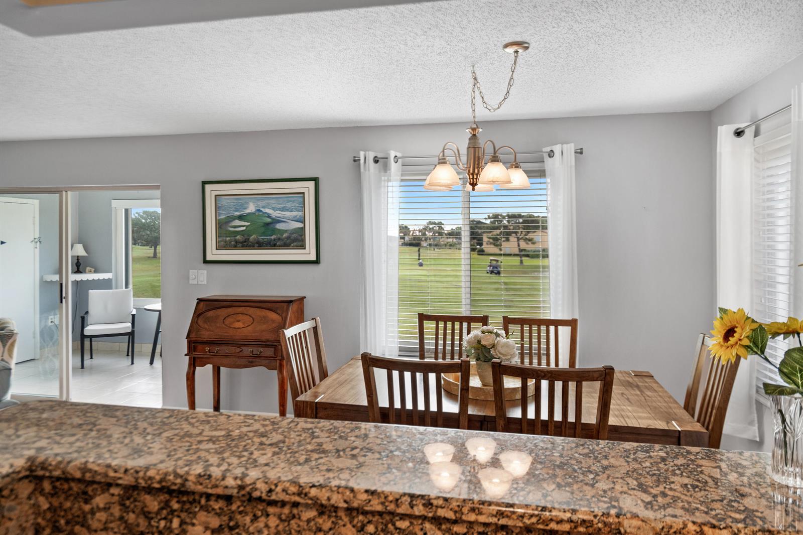 A dining area features a wooden table, chairs, a chandelier, and a view of a golf course — 5393 SE Miles Grant Road SE # 202, Stuart FL 34997, STUART, FL
