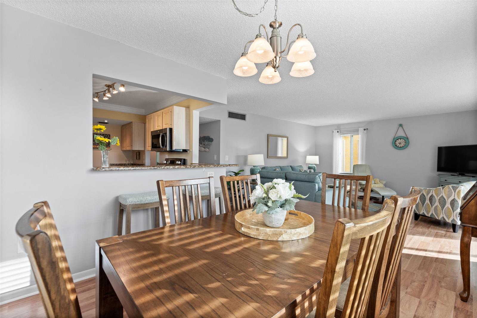 A dining area with a wooden table and chairs opens into a living room — 5393 SE Miles Grant Road SE # 202, Stuart FL 34997, STUART, FL