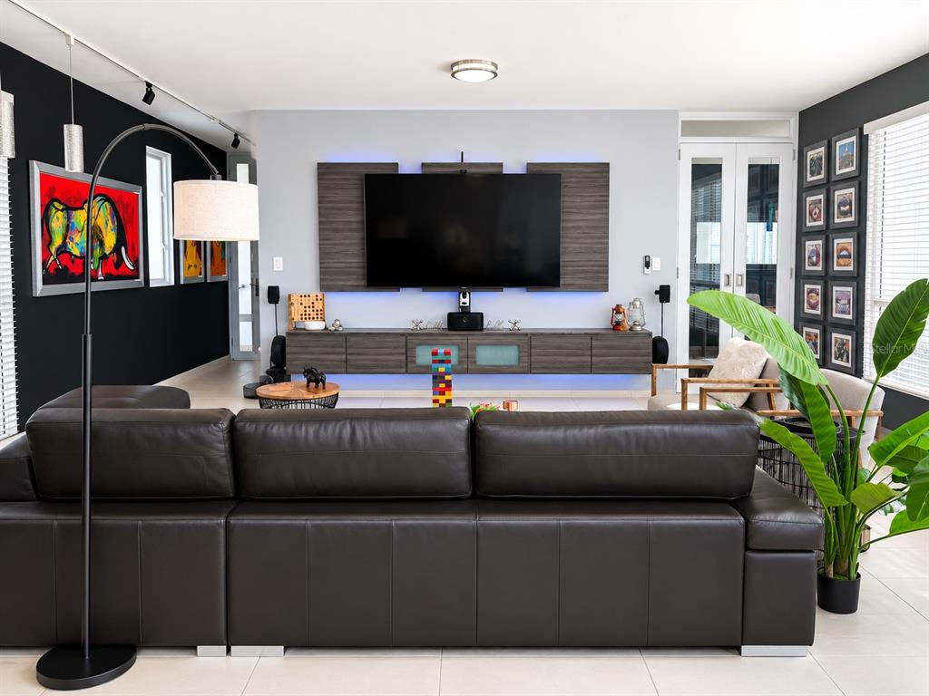 A modern living room features a dark leather sectional, a wall-mounted television, and black walls — 1554 López Landron St. COND. CONDADO LES COURS UNIT PH 503, SAN JUAN, PR