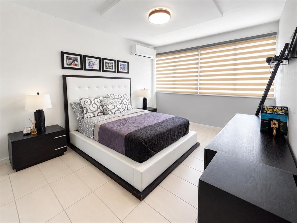 A bedroom features a white platform bed, dark wood furniture, and horizontal window blinds — 1554 López Landron St. COND. CONDADO LES COURS UNIT PH 503, SAN JUAN, PR