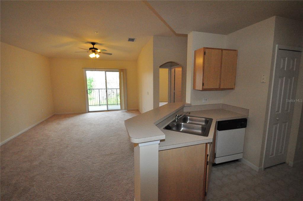 A kitchen with a breakfast bar overlooks a carpeted living area with a sliding glass door — 6530 SWISSCO DRIVE UNIT 1134, ORLANDO, FL