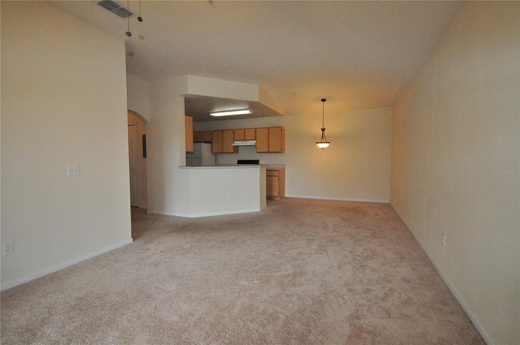 A carpeted living room opens to a kitchen with light wood cabinets and a breakfast bar — 6530 SWISSCO DRIVE UNIT 1134, ORLANDO, FL