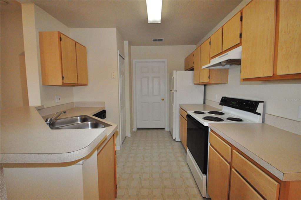 A kitchen features light wood cabinets, laminate countertops, a white stove, and a white refrigerator — 6530 SWISSCO DRIVE UNIT 1134, ORLANDO, FL