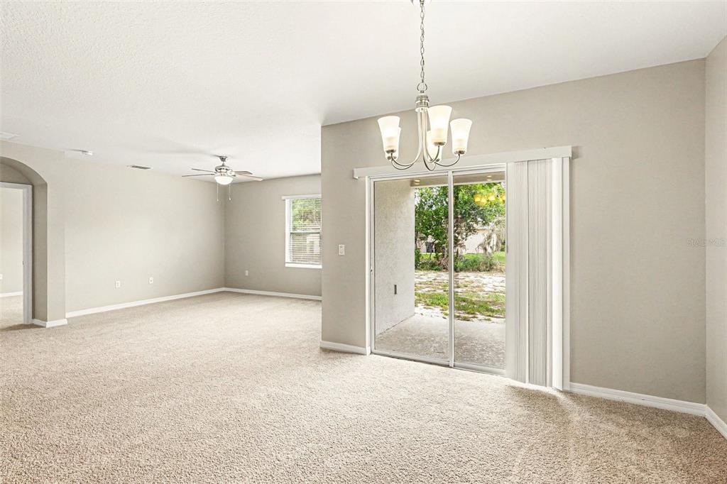 A carpeted living area features a sliding glass door, a chandelier, and a ceiling fan — 996 SUMMER GLEN DRIVE, WINTER HAVEN, FL