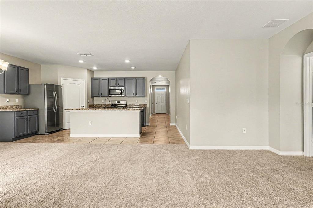 An open-concept kitchen with gray cabinets and a breakfast bar overlooks a carpeted living area — 996 SUMMER GLEN DRIVE, WINTER HAVEN, FL