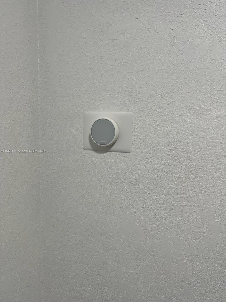 A white smart thermostat is mounted on a textured white wall — 7710 NE 1st Ct, Miami FL 33138, MIAMI, FL