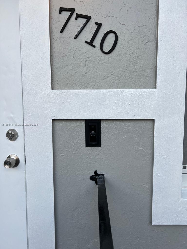 A close-up view of a white door with a doorbell camera and house number 7710 — 7710 NE 1st Ct, Miami FL 33138, MIAMI, FL