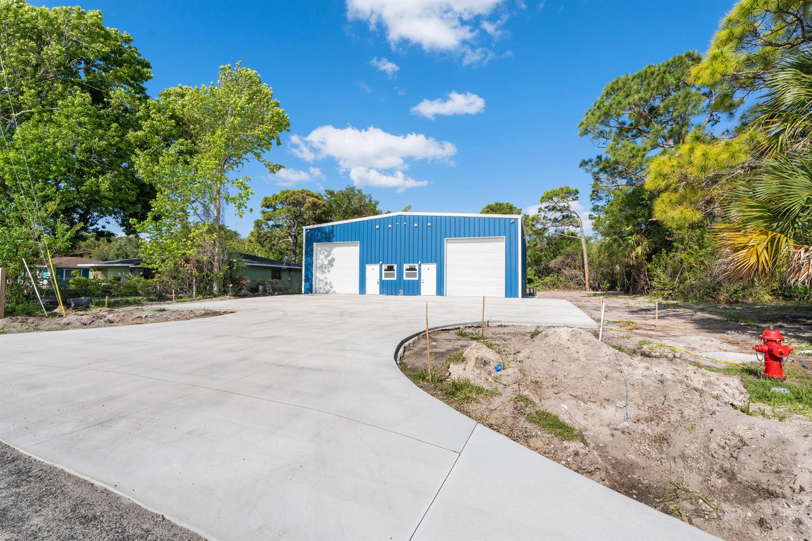 A blue metal warehouse building stands behind a large, newly poured concrete driveway — 2933 Harson Way, Fort Pierce FL 34946, FORT PIERCE, FL