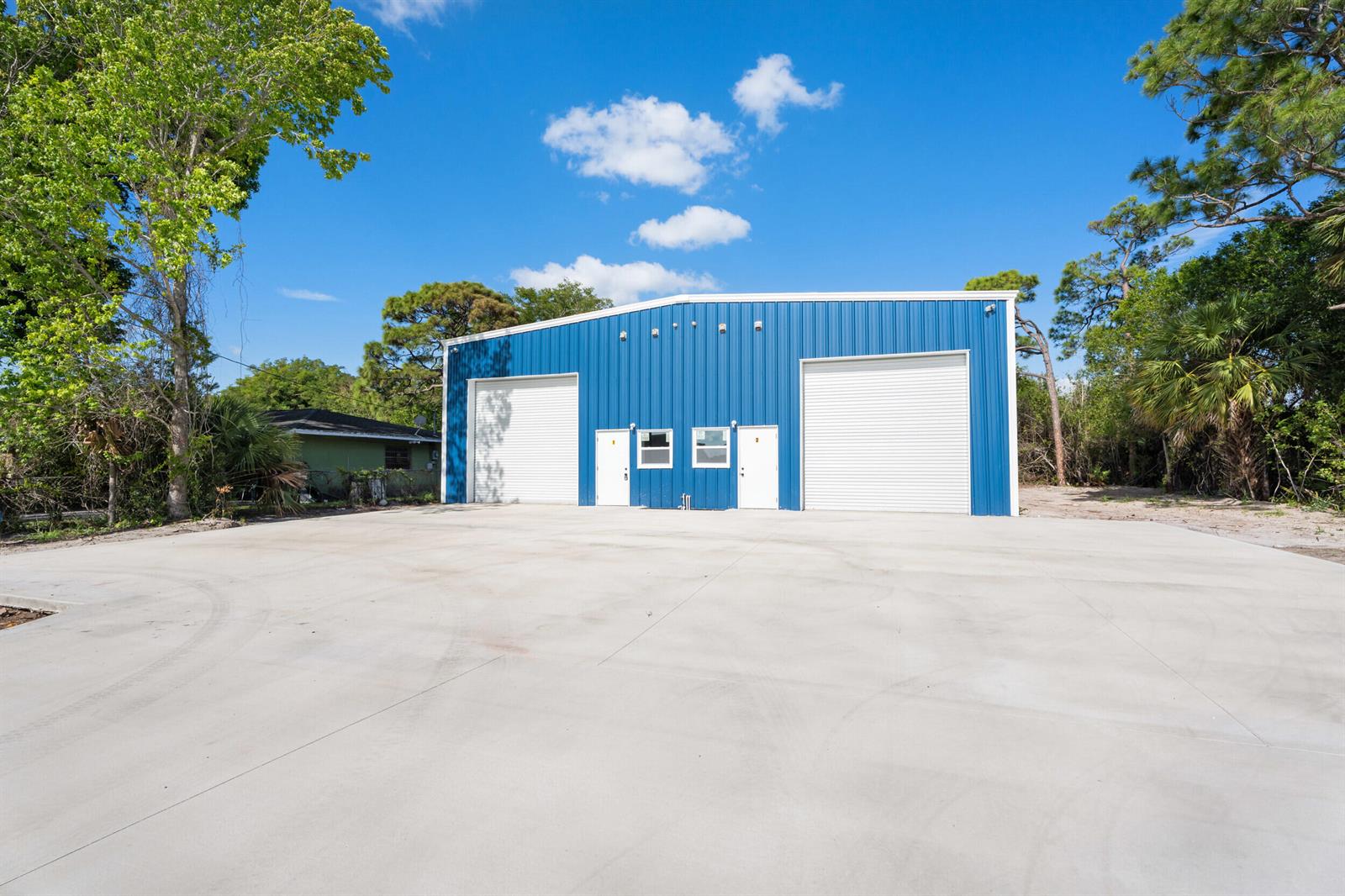 A blue metal warehouse building features two roll-up garage doors and two entry doors — 2933 Harson Way, Fort Pierce FL 34946, FORT PIERCE, FL
