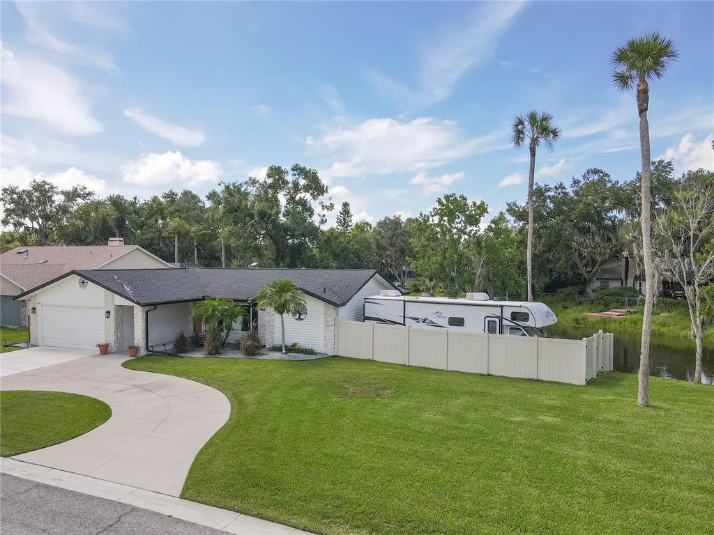 A single-story house with a white exterior, a concrete driveway, and an RV parked behind fencing — 7905 55TH STREET E, PALMETTO, FL