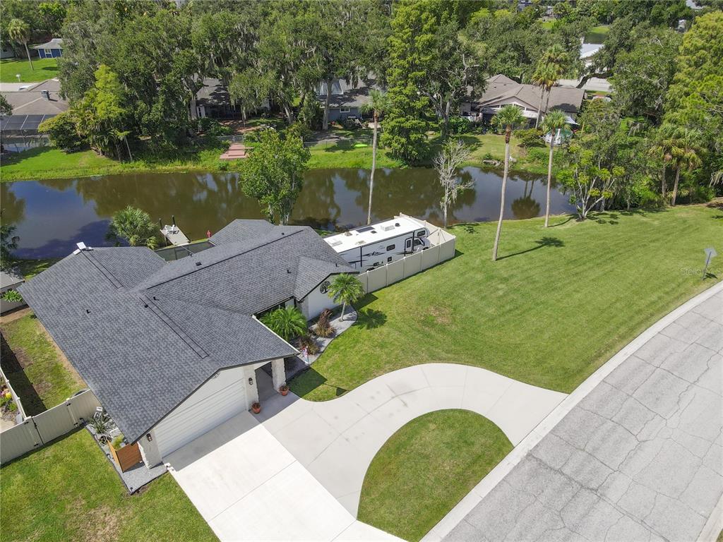 An aerial view shows a house with a gray roof, a driveway, and a backyard pond — 7905 55TH STREET E, PALMETTO, FL