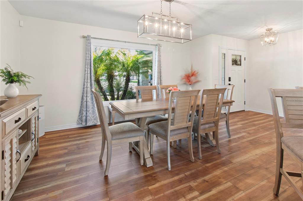 A dining room features a wooden table, six chairs, a sideboard, and a large window — 7905 55TH STREET E, PALMETTO, FL