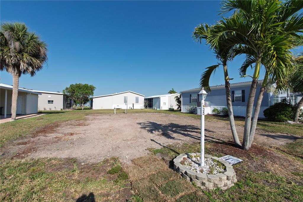 A vacant dirt lot sits between two manufactured homes under a clear blue sky — 35 AMSTERDAM AVENUE, PUNTA GORDA, FL
