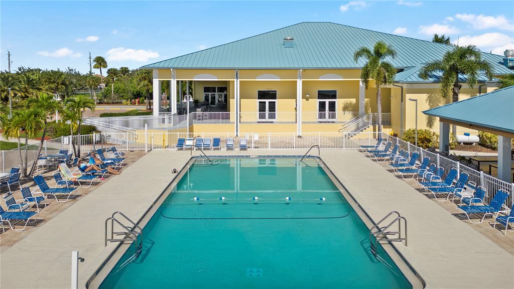 A rectangular swimming pool sits in front of a yellow building with a metal roof — 35 AMSTERDAM AVENUE, PUNTA GORDA, FL