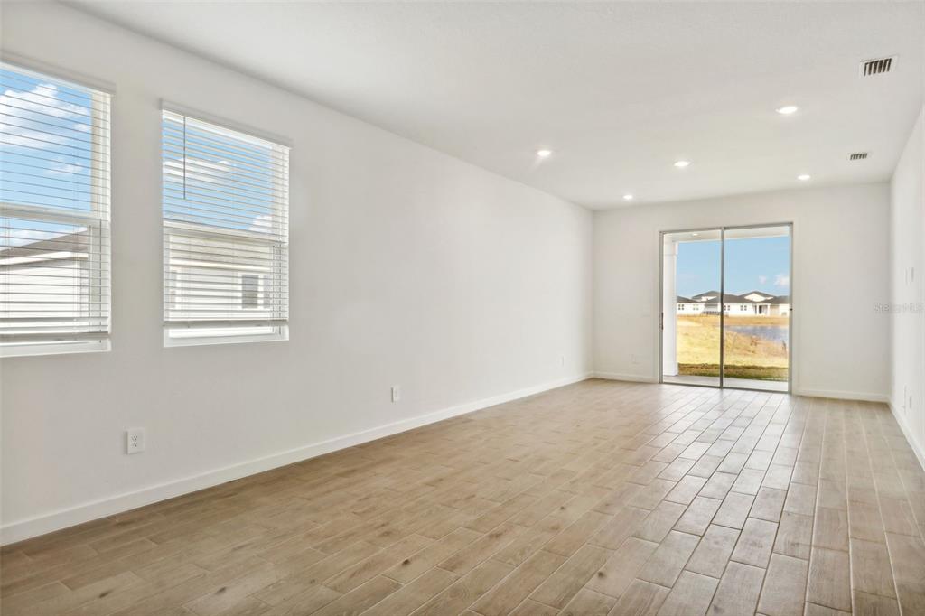 An empty room with light-colored tile flooring, white walls, two windows, and sliding glass doors — 75 WANDERING CREEK WAY, PALM COAST, FL