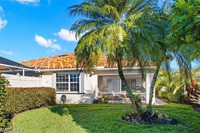 A backyard view of a house with a tiled roof, screened-in patio, and palm tree — 3144 Andorra CT, Naples FL 34109, NAPLES, FL