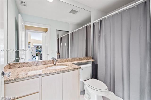 A bathroom features a granite countertop, a light wood vanity, and a gray shower curtain — 3144 Andorra CT, Naples FL 34109, NAPLES, FL