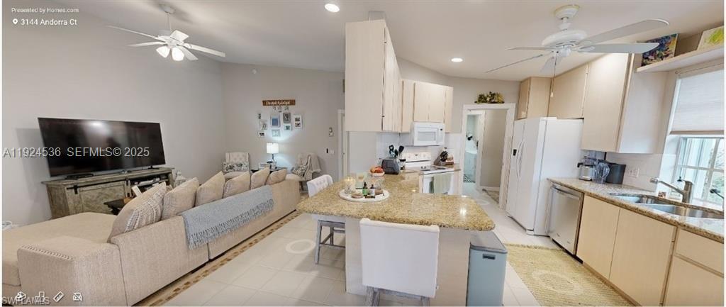 An open-concept living room and kitchen feature light-colored cabinetry, granite countertops, and tile flooring — 3144 Andorra CT, Naples FL 34109, NAPLES, FL