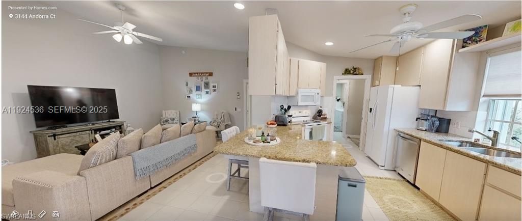 An open-concept living room and kitchen feature light-colored cabinetry, granite countertops, and tile flooring — 3144 Andorra CT, Naples FL 34109, NAPLES, FL