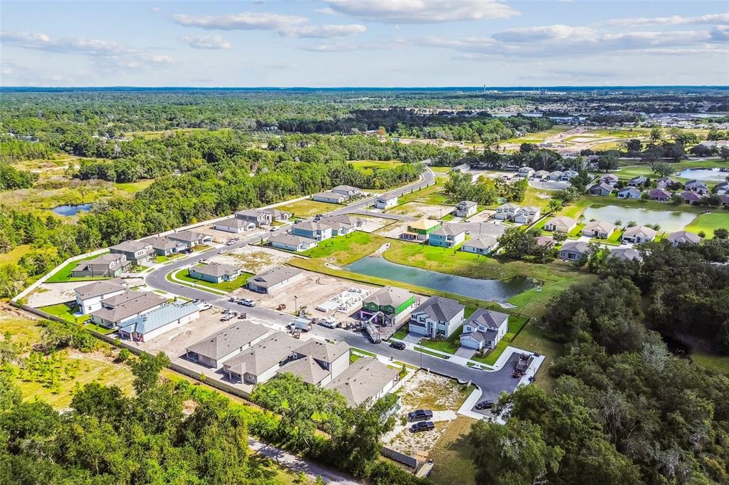 An aerial view shows a suburban neighborhood under construction with several houses and a pond — 13686 BERRYWOOD COURT, HUDSON, FL