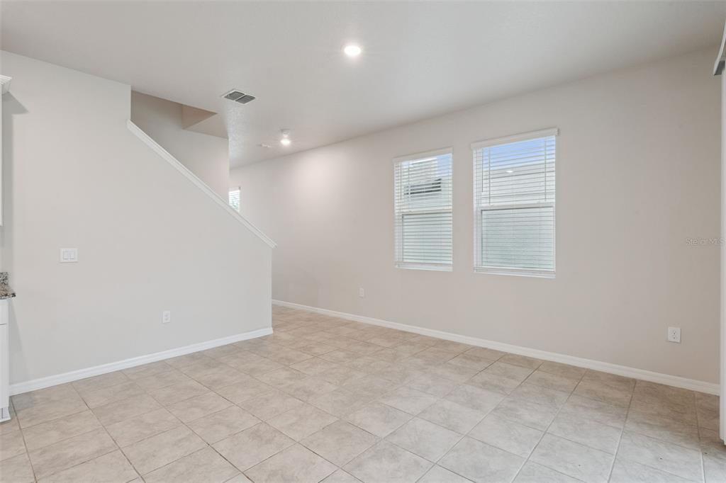An empty room with light-colored tile flooring, beige walls, and two windows with blinds — 2292 MYSTIC MAZE LANE, CLERMONT, FL