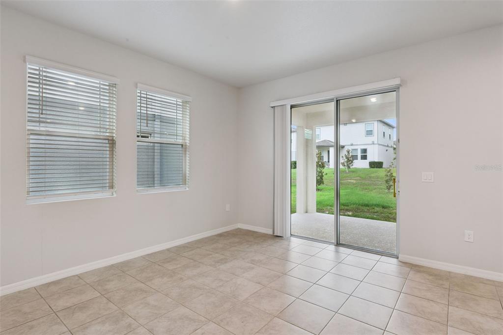 An empty room with light tile flooring, two windows with blinds, and a sliding glass door — 2292 MYSTIC MAZE LANE, CLERMONT, FL