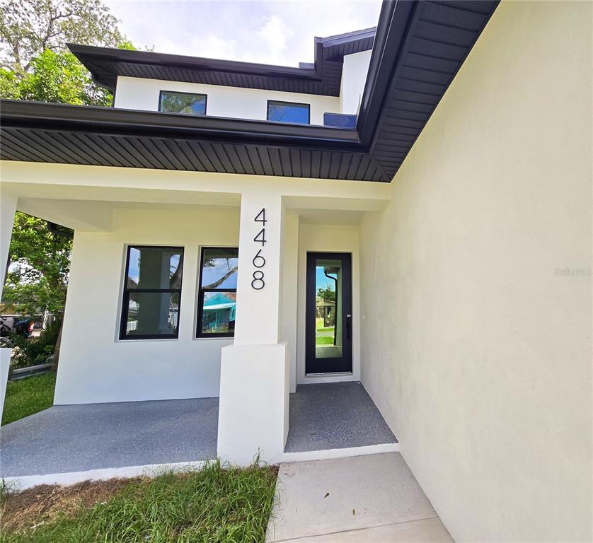 A covered patio features white walls, two black-framed windows, and a black-framed glass door — 4468 57TH AVENUE N, ST PETERSBURG, FL