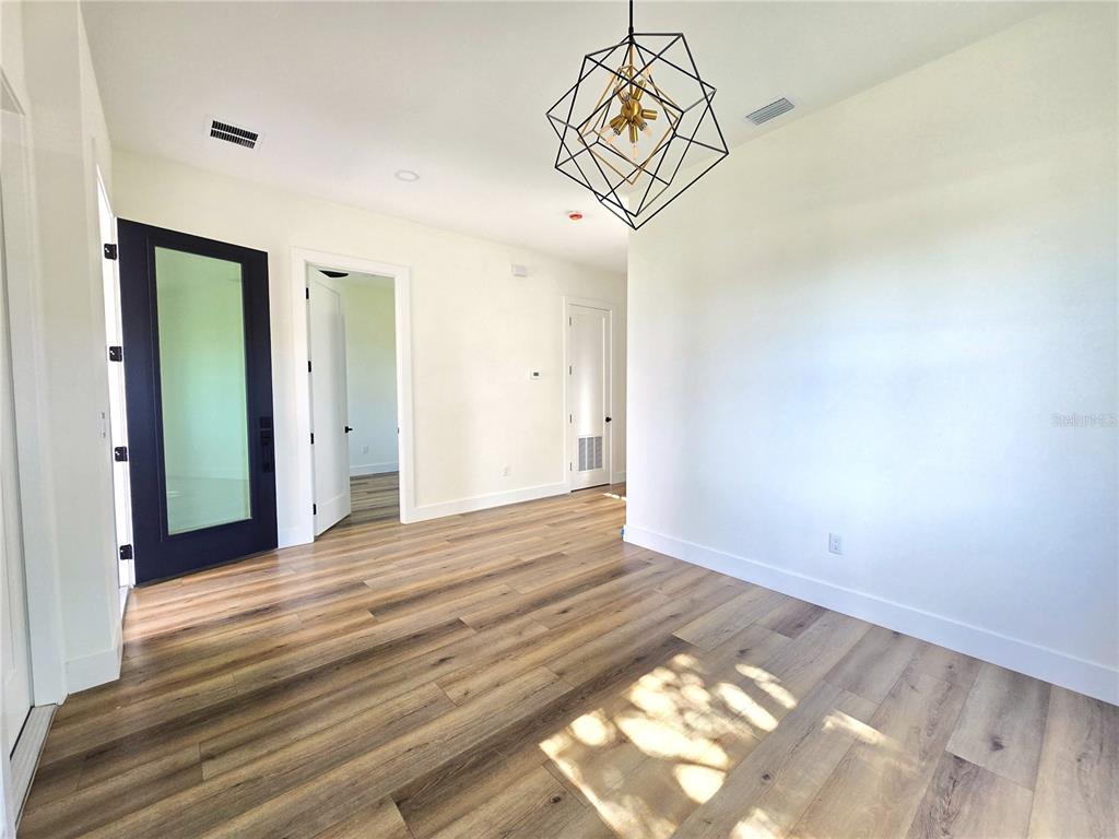 A bright entryway features wood-look flooring, a staircase with a black railing, and an open kitchen — 4468 57TH AVENUE N, ST PETERSBURG, FL