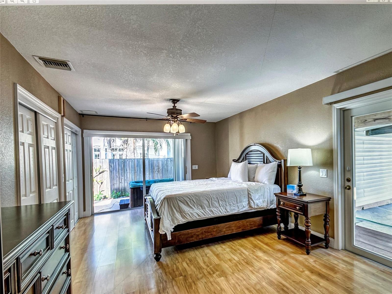 A bedroom features a wooden bed, a ceiling fan, wood flooring, and sliding glass doors — 141 Rutland Boulevard, West Palm Beach FL 33405, WEST PALM BEACH, FL