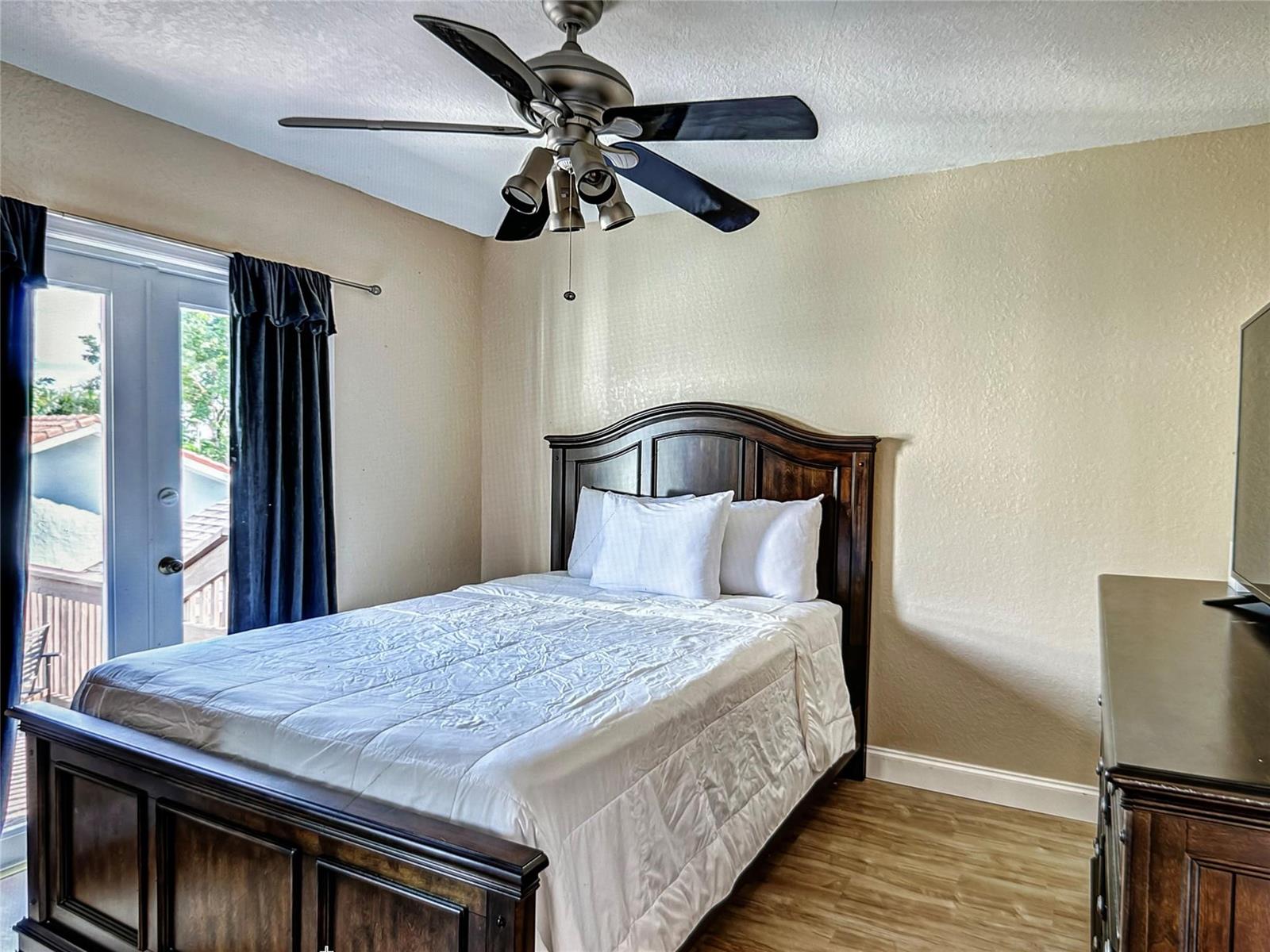 A bedroom features a dark wood bed frame, a ceiling fan, and a glass door — 141 Rutland Boulevard, West Palm Beach FL 33405, WEST PALM BEACH, FL