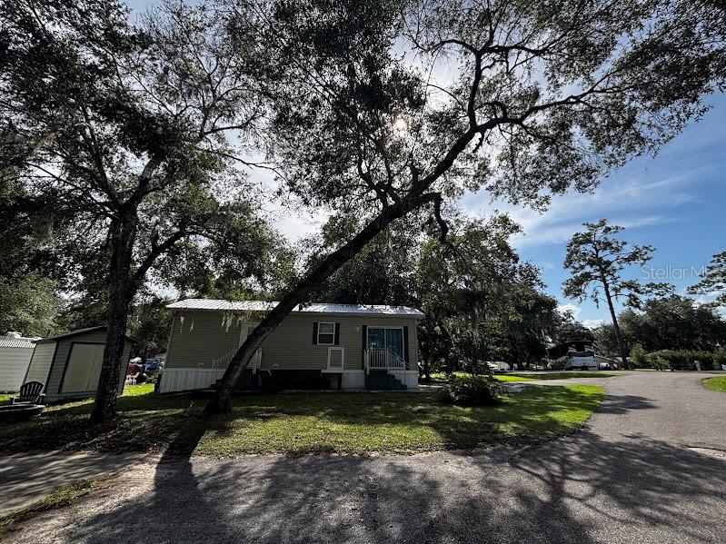 A manufactured home sits on a grassy lot shaded by large, mature oak trees — 25296 141ST STREET NE UNIT 380, FORT MC COY, FL