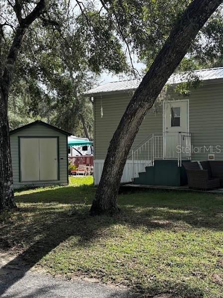 A light-colored house with a shed and a large tree in the front yard — 25296 141ST STREET NE UNIT 380, FORT MC COY, FL