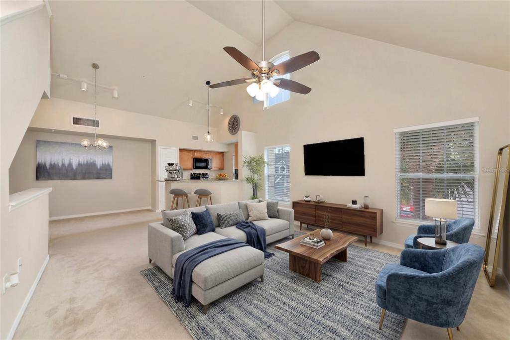 A living room with vaulted ceilings, a sectional sofa, two blue chairs, and a kitchen — 5560 ROSEHILL ROAD UNIT 201, SARASOTA, FL