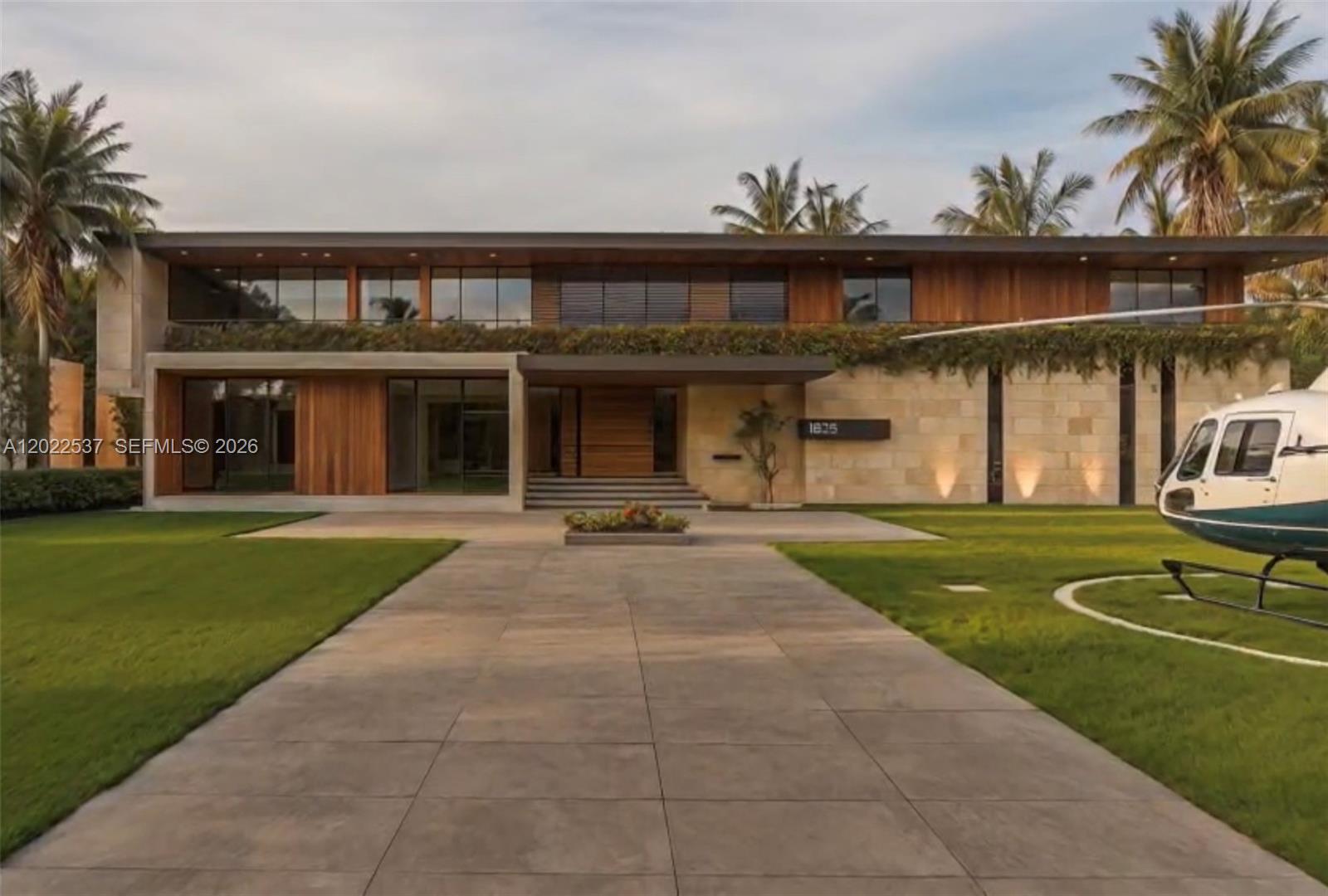 A modern two-story house with wood siding, stone walls, and a helicopter parked on the lawn — 18105 SW 158th St, Miami FL 33187, MIAMI, FL