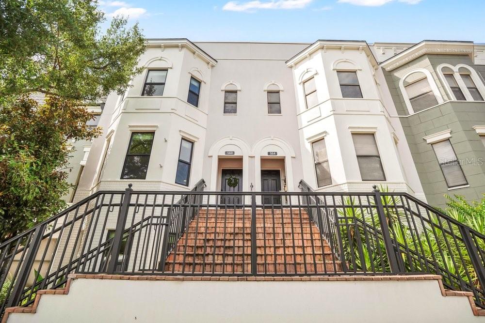 A low-angle view of two adjacent townhomes with stairs leading to their front entrances — 560 COPLEY LANE, ORLANDO, FL
