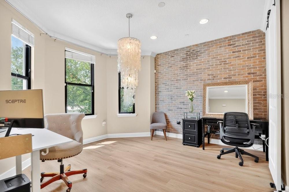A home office features light wood flooring, a brick accent wall, and a crystal chandelier — 560 COPLEY LANE, ORLANDO, FL
