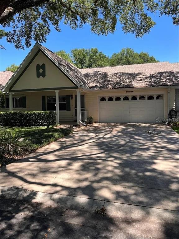 A single-story house with a beige exterior, a two-car garage, and a front-facing gable — 8591 SW 93RD PLACE UNIT E, OCALA, FL