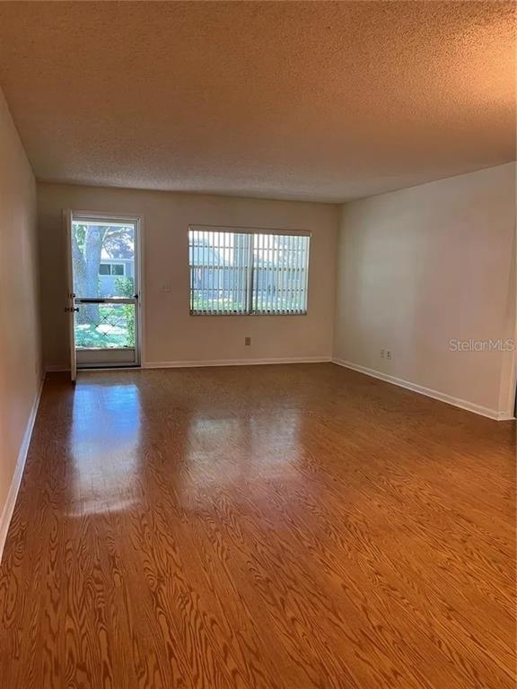 An empty room features wood-look flooring, a window with vertical blinds, and a glass-paneled door — 8591 SW 93RD PLACE UNIT E, OCALA, FL