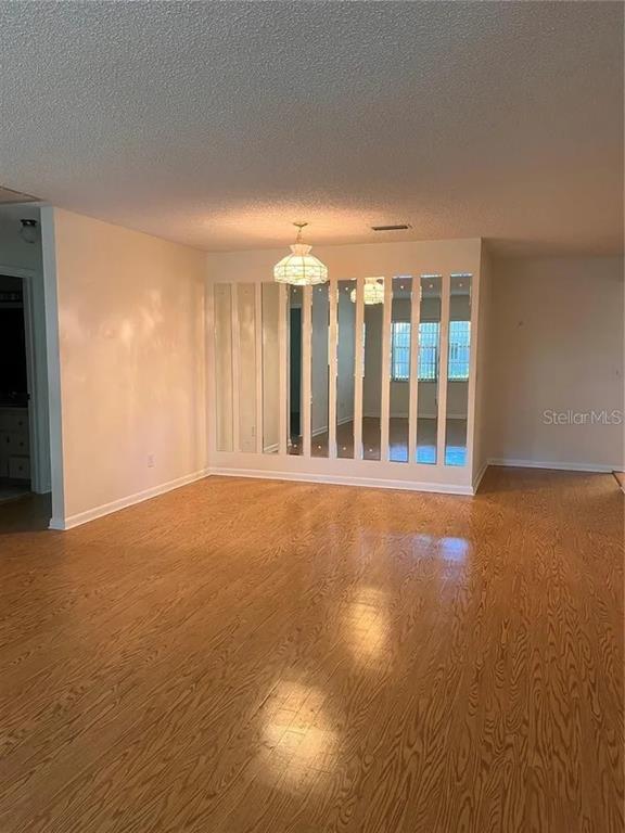 A room with wood-look flooring features a wall of vertical mirror panels and a chandelier — 8591 SW 93RD PLACE UNIT E, OCALA, FL