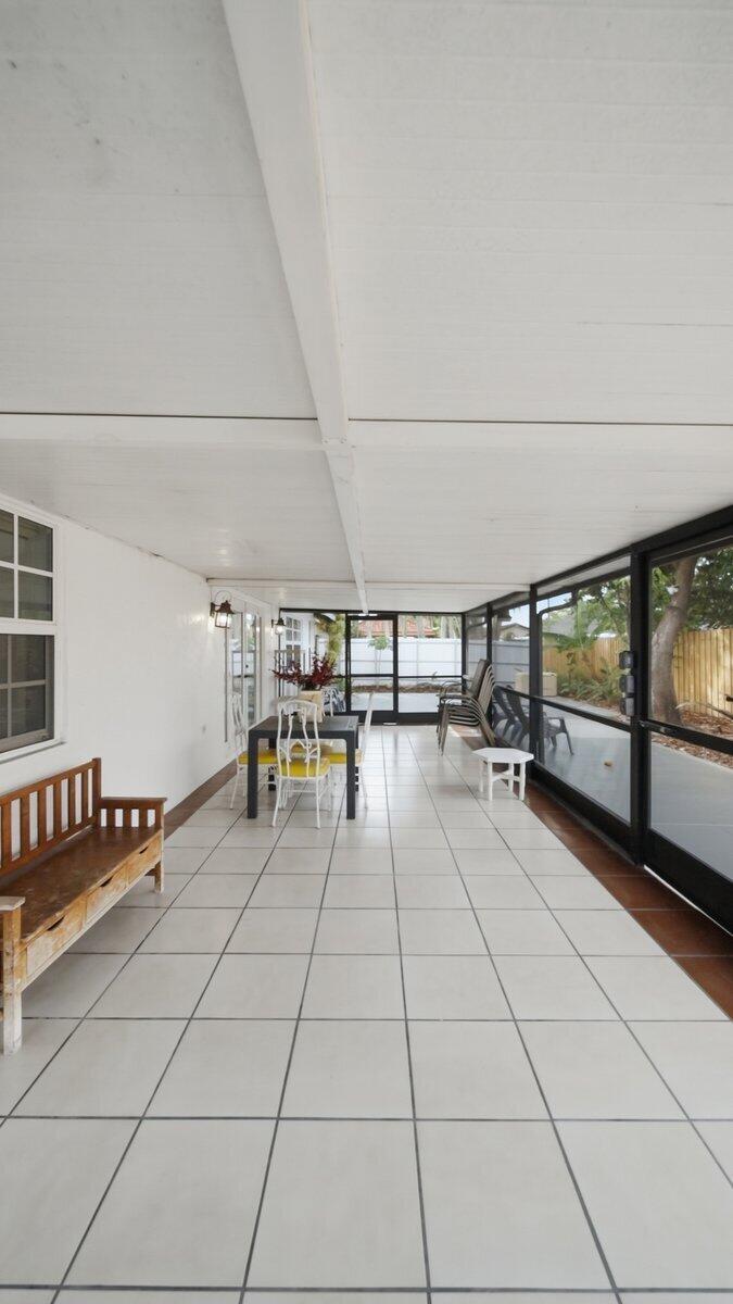A screened-in patio features white tiled flooring, a wooden bench, and a dining set — 20009 NW 66th Place, Hialeah FL 33015, HIALEAH, FL