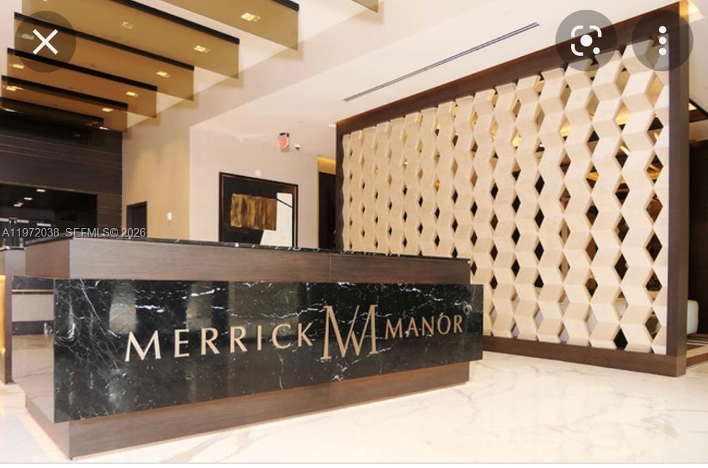 A modern lobby features a dark marble reception desk and a geometric decorative screen wall — 301 Altara Ave # 701, Coral Gables FL 33146, CORAL GABLES, FL