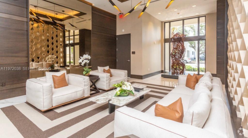 A modern lobby features white sofas, brown accent pillows, a marble coffee table, and sculpture — 301 Altara Ave # 701, Coral Gables FL 33146, CORAL GABLES, FL