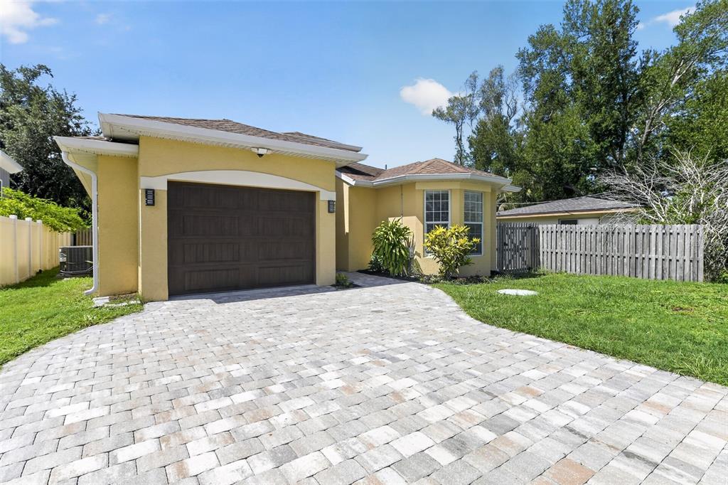 A yellow single-story house features a brown garage door and a paved stone driveway — 1816 RITA STREET, SARASOTA, FL